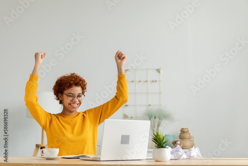 Excited happy african american woman euphoric winner. Girl student looking at laptop passed exam reading great news getting good result winning online bid feeling amazed at home. Winning gesture