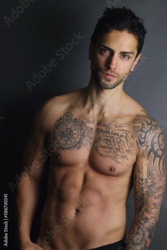 Handsome man with tattoo posing on gray background