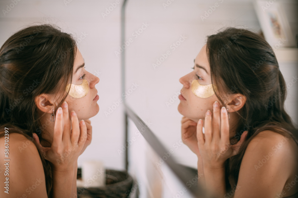Young woman with patches under her eyes at the mirror at home. Young woman with patches under her eyes at the mirror at home.