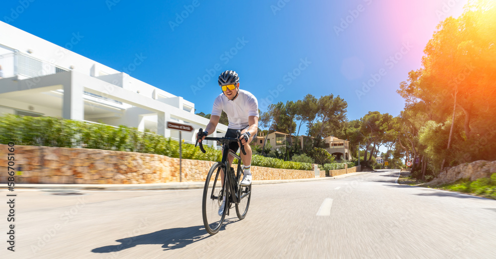 Man Adult on a racing bike climbing the hill at mediterranean sea landscape coastal road on mallorca balearic island
