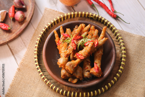 Ceker mercon or claw fireworks a food made from chicken claws cooked with chilies, onions and flavoring. served on clay plate, wooden plate and brown napkin. photo