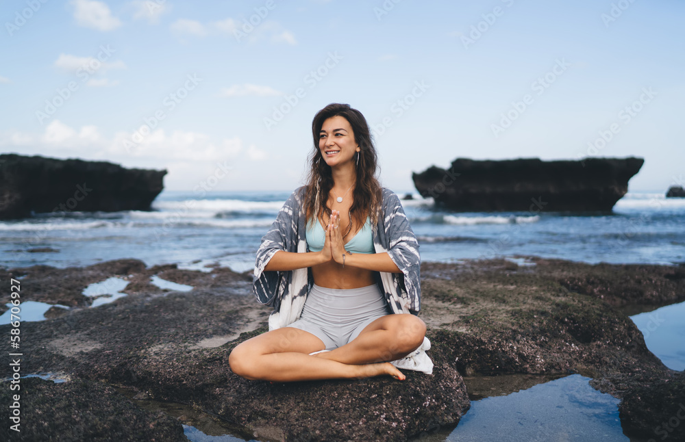 Young woman sitting on beach stone in mudra