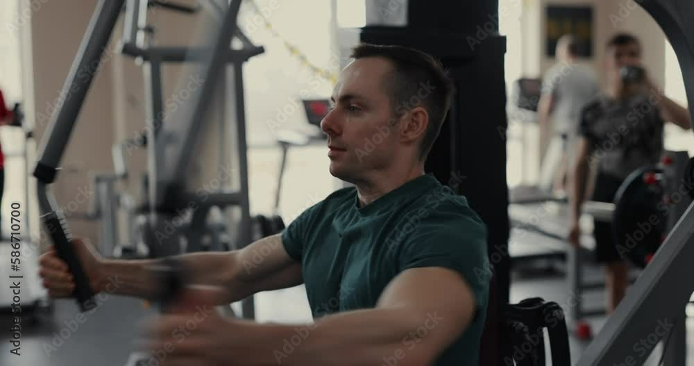 A man doing butterfly exercise on a training apparatus in the gym pumping pectoral muscles A man doing butterfly exercise on a training apparatus in the gym pumping pectoral muscles