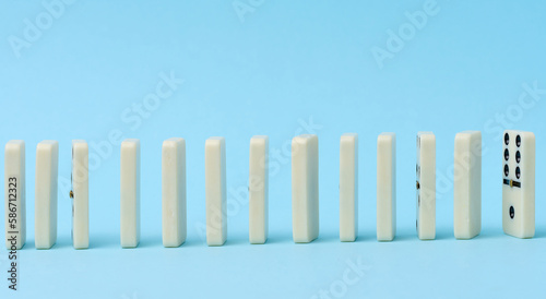 Dominoes standing in a row on a blue background  gambling