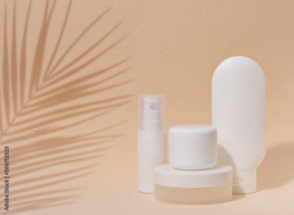 White plastic container tube, a jar with a lid for cosmetics on a beigebackground with a shadow from a palm leaf. Advertising and promotion White plastic container tube, a jar with a lid for cosmetics on a beigebackground with a shadow from a palm leaf. Advertising and promotion