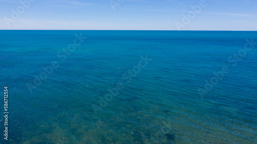 Aerial view of the blue waters of the Mediterranean Sea and specifically of the Tyrrhenian Sea from Sardinia. Sunlight is reflected on the surface of the water. Sky is on background.
