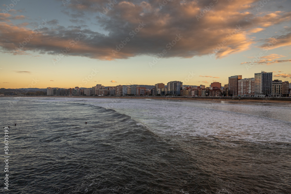 Exposure from the Gijon boardwalk of the beautiful seafront with great waves for surfing at Sunset, Spain.