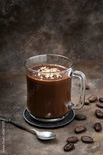 Thick spicy hot chocolate in glas cup on dark background