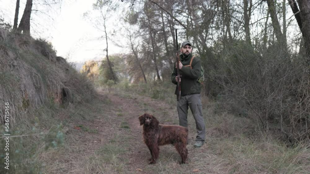Hunter man looking around searching for prey while hunting with his dog outdoors. Hunter man looking around searching for prey while hunting with his dog outdoors.