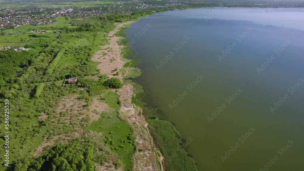 This drone video shows a beautiful lake surrounded by dense forest. The water on the lake is calm and transparent, reflecting the greenery of the trees and the blue sky. The shore of the lake is decor This drone video shows a beautiful lake surrounded by dense forest. The water on the lake is calm and transparent, reflecting the greenery of the trees and the blue sky. The shore of the lake is decor