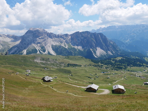 Mount Seceda, Ortisei, Bolzano Bozen, Italy: panoramic view of meadow and mountain huts from mount Seceda, with Mount Stevia, Dolomites, in the background