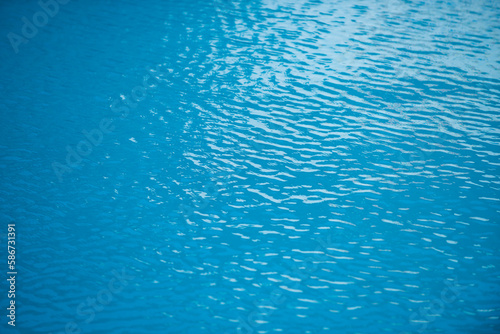 Blue pool water background. Blurred transparent clear calm water surface texture. Water waves in sunlight with copy space.