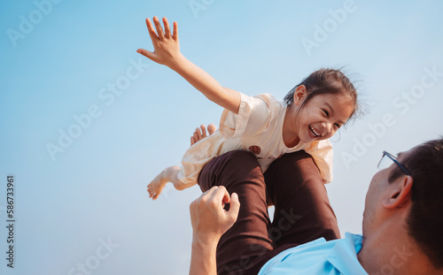 Happy family in the park on weekend. family enjoying together in the meadow with river Parents hold the daughter.health life insurance plan concept.