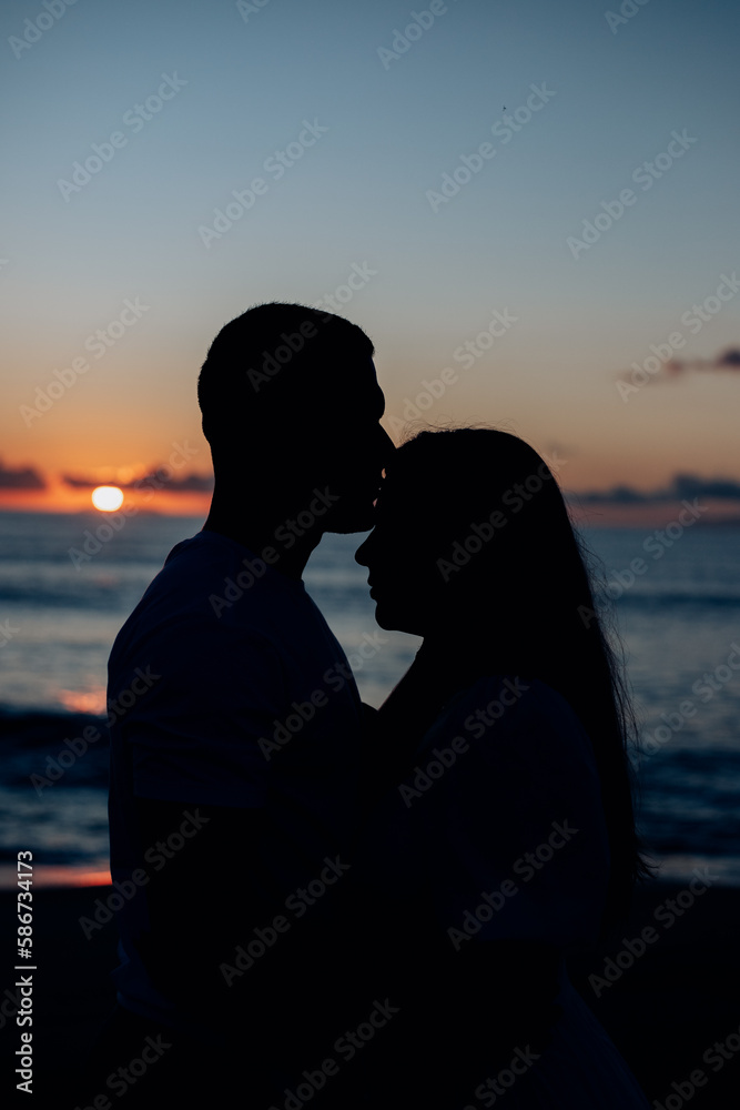 silhouette of couple kissing on the beach at sunset