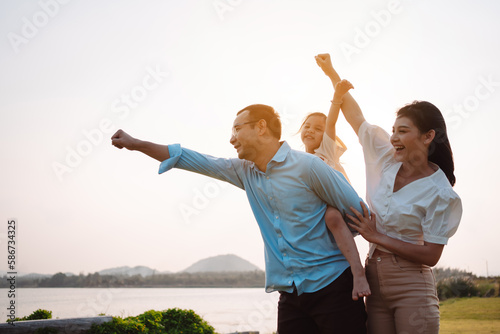 Happy family in the park sunset light. family on weekend running together in the meadow with river Parents hold the child hands.health life insurance plan concept.