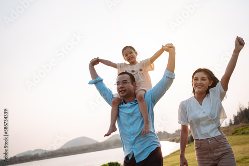 Happy family in the park sunset light. family on weekend running together in the meadow with river Parents hold the child hands.health life insurance plan concept. © Kiattisak