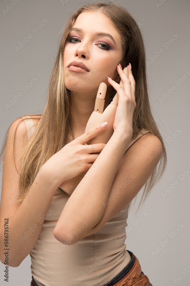 Attractive girl in blue jeans and long hair posing challenging in front of a background with wood hand in hes hands. Attractive girl in blue jeans and long hair posing challenging in front of a background with wood hand in hes hands.