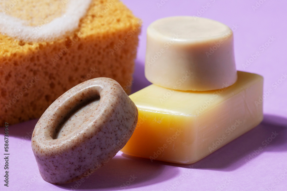 Handmade soap with the addition of coffee and wild herbs and a sponge with foam on a purple background.