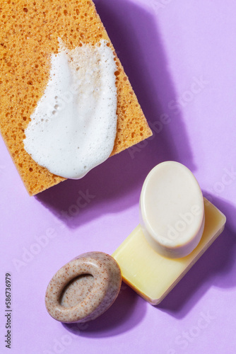 Obraz na płótnie Handmade soap with the addition of coffee and wild herbs and a sponge with foam on a purple background. w salonie