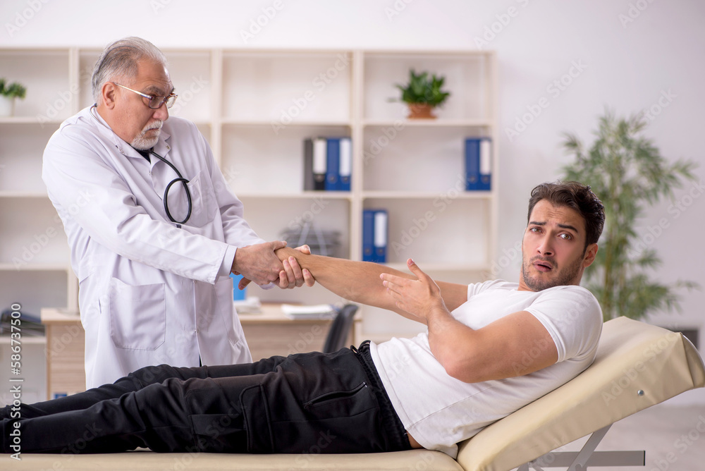 Obraz premium Young male doctor visiting old doctor chiropractor