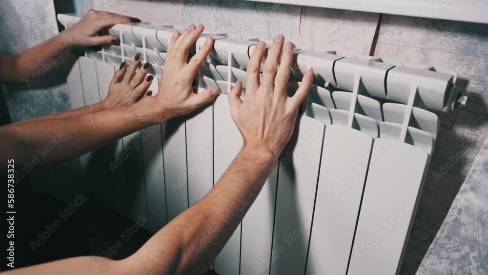 Hands are warmed by heating radiators. Frozen male and female hands