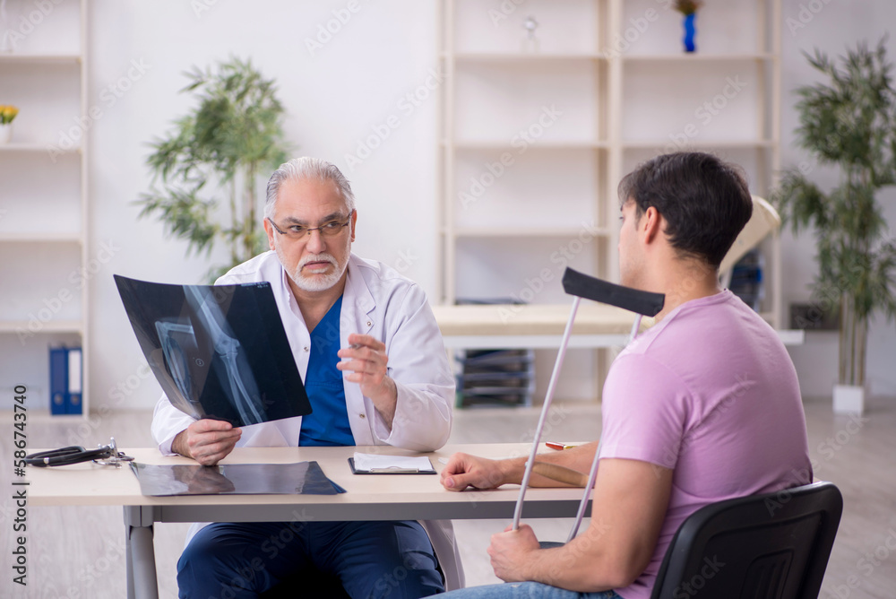 Young leg injured patient visiting old male doctor radiologist Young leg injured patient visiting old male doctor radiologist