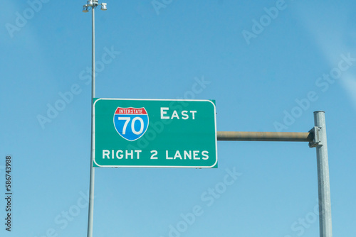 overhead brightly colored steel highway sign for interstate 70 east right two lanes of high way exit ahead