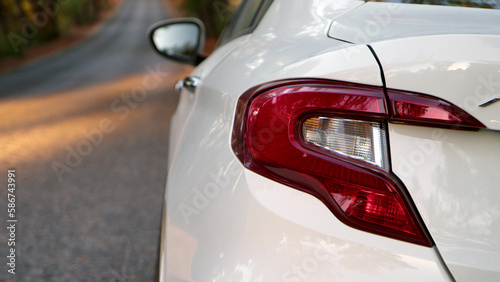 close view of rear light of white passenger car. passenger car stands parked near road on side of road  close-up of fashionable modern tail light lamp.