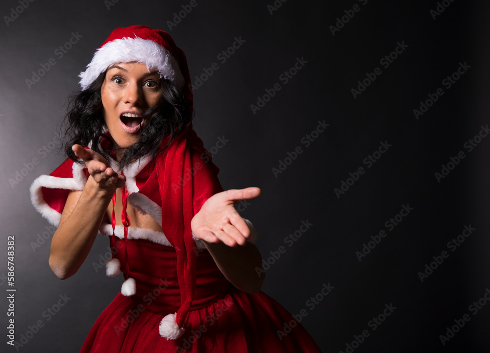 A woman in a Christmas dress shows her finger. One hand on the belt. Black background A woman in a Christmas dress shows her finger. One hand on the belt. Black background