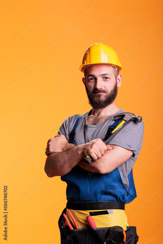 Carpenter expert holding sledgehammer on camera, posing in studio shot. Confident construction worker using hammer or mallet to hit nails, working on professional refurbishment job.