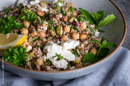Bild auf Leinwand Healthy Salad made from Quinoa, Cucumber, Herbs, Pistachios, Chickpeas and Feta with lemon juice and olive oil
