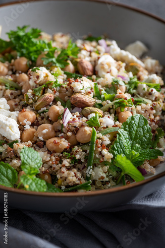 Healthy Salad made from Quinoa, Cucumber, Herbs, Pistachios, Chickpeas and Feta with lemon juice and olive oil. So called Jennifer Aniston Salad, fresh, crunchy, and packed with plant-based protein photo