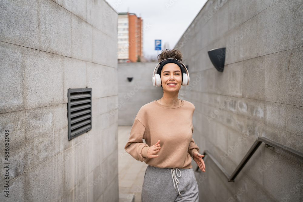 One young sporty woman with headphones use mobile run on steps jogging