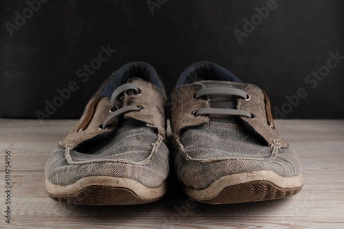 Blurred image of old shoes standing on the floor against a dark wall.