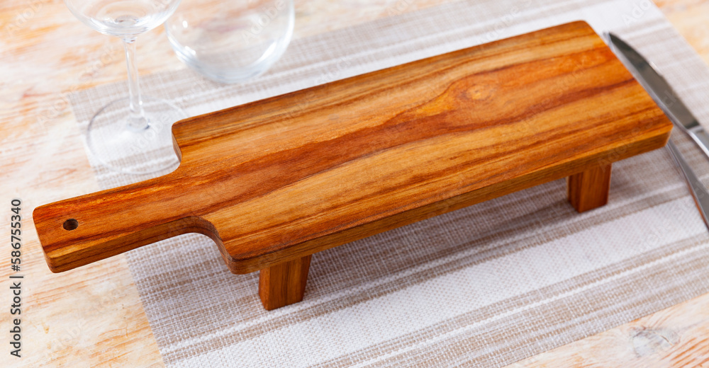 Closeup of empty natural wooden board for serving variety of breakfast items. Kitchen utensils for decorative and functional purposes