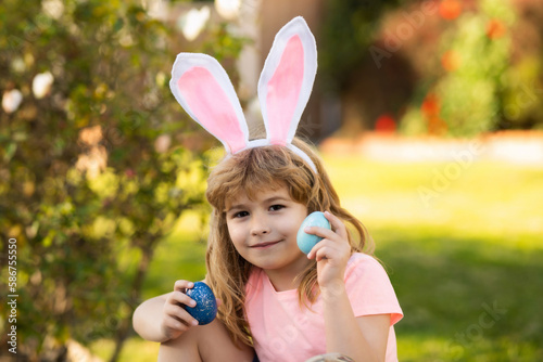 Child boy hunting easter eggs. Kid with easter eggs and bunny ears outdoor. Spring holidays.
