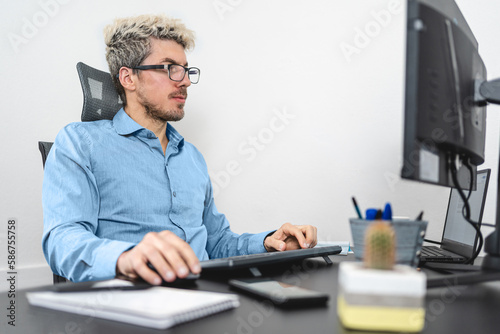 Caucasian office worker sitting on the desk with the computer.