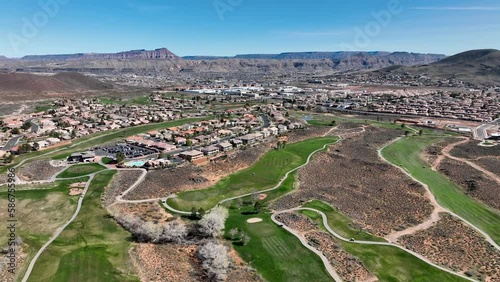 Aerial southern Utah desert golf course homes. Subdivision neighborhood residential homes. Mountain valley desert. Hot environment. Housing boom economy. Nature landscape scenic red rock.