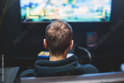 Process of playing video games, video game console with wireless controller, male gamer on a couch with black joystick in front of big wide screen tv