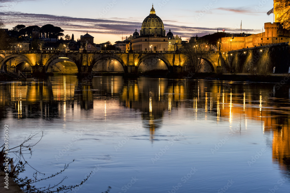 Incredible day to night sunset of Rome, Italy, with the Ponte Sant'Angelo, the River Tiber with reflections on the water and St. Peter's Basilica in the Vatican.