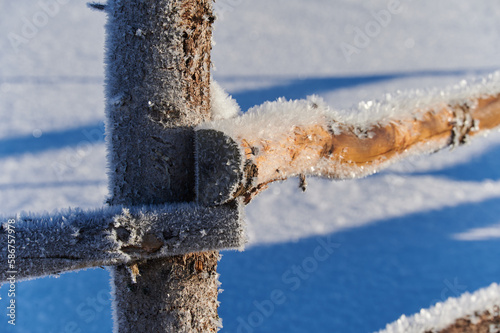 Close up view of wooden fence covered with frozen patterns.