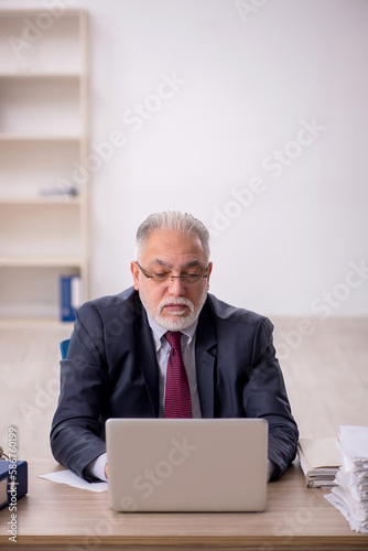 Old male employee sitting at workplace