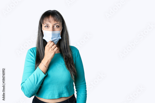 Young woman wearing medical mask and looking at camera. Isolated on white background. © Pajaros Volando