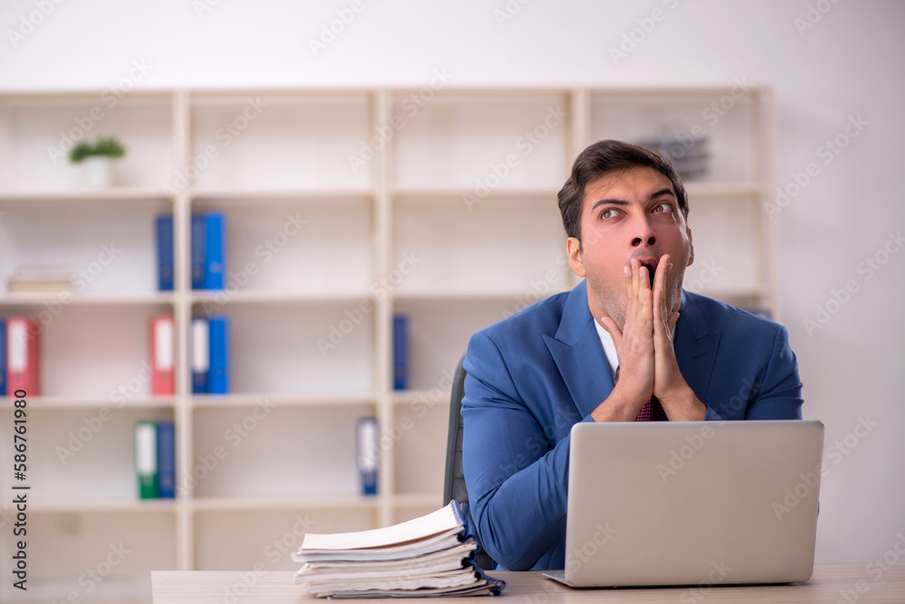 Young male employee and too much work in the office Young male employee and too much work in the office