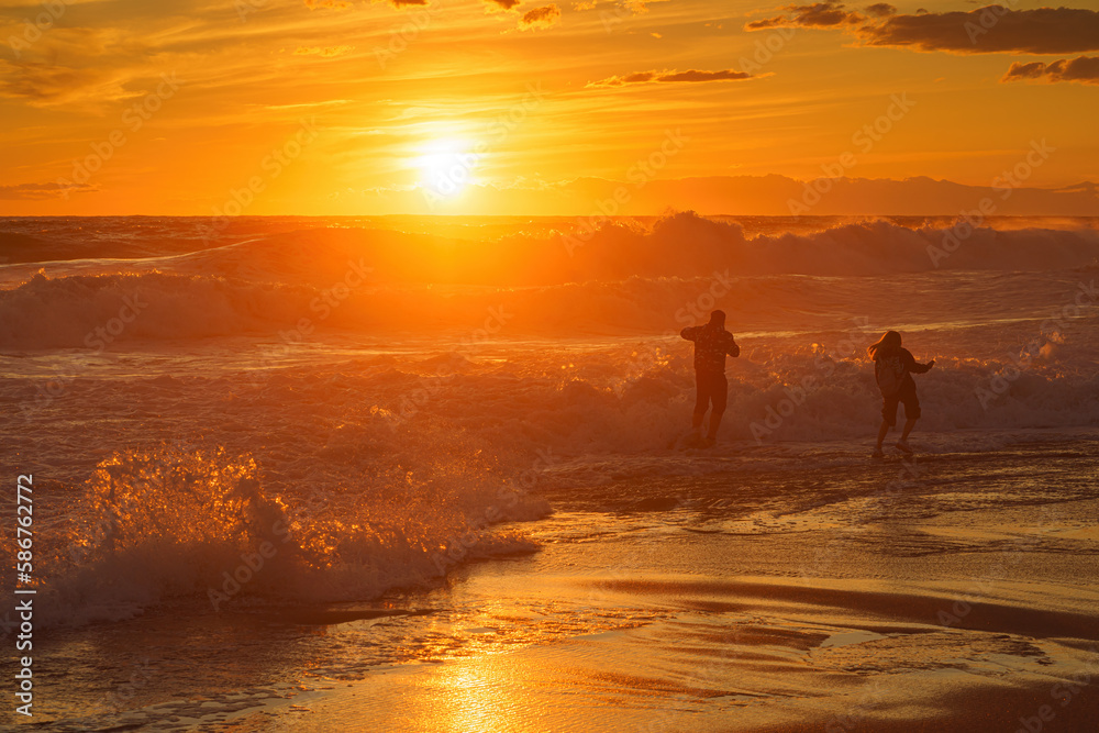 Dangerous games. Two people play in the waves at sunset. Storm, Mediterranean Sea, Türkiye