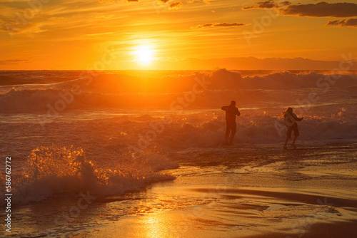 Dangerous games. Two people play in the waves at sunset. Storm, Mediterranean Sea, Türkiye
