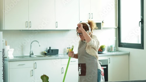 Carefree happy young woman cleaning house living room have fun dancing with mop, smiling overjoyed millennial girl feel excited enjoy making home chores sing entertain using floor broom or Swiffer
 photo