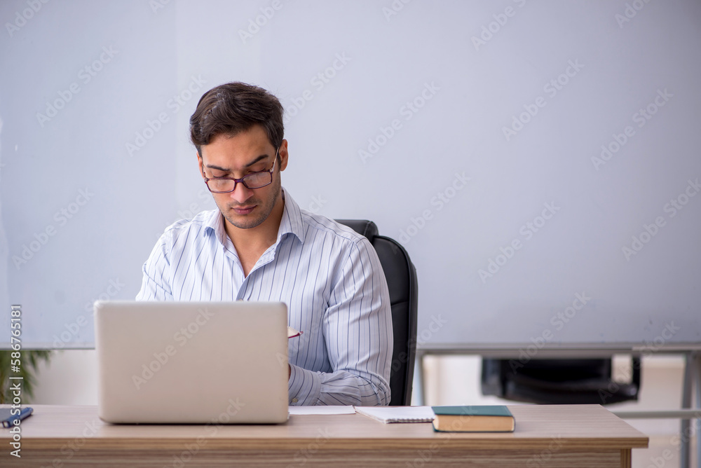 Young male teacher sitting in the classroom Young male teacher sitting in the classroom
