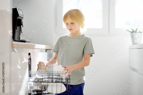 Fotografie A preteen boy is loading dirty dishes into the dishwasher