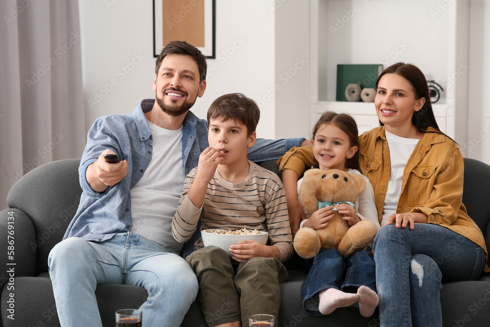 Happy family watching TV at home. Father changing channels with remote control Happy family watching TV at home. Father changing channels with remote control